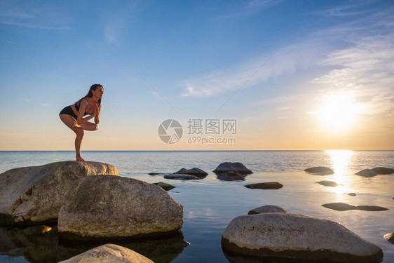 全身瘦的雌手握在宁静海边岩石上平衡在晚图片