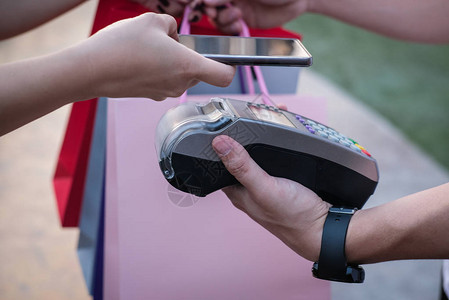 女人使用智能手机通过电子阅读器进行移动支付客户使用近场通信NFC技术付款人们使用手机中的应用程序图片