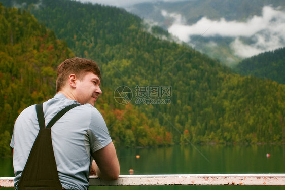 穿着远足服装的年轻人在秋日观看美丽的高山湖泊针图片