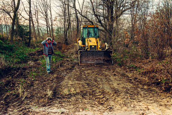2020年森林中的工人和黄色旧挖土机挖图片
