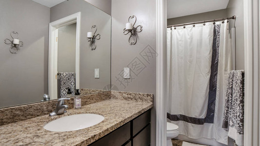 全景框架家庭浴室配有灰色墙壁棕色木柜和大理石台面图片