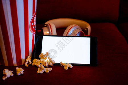 红沙发上有空白亮银幕和爆米花桶的手机图片