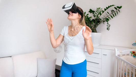 年轻女在虚拟现实的眼镜或耳机上观看360度全景视频图片