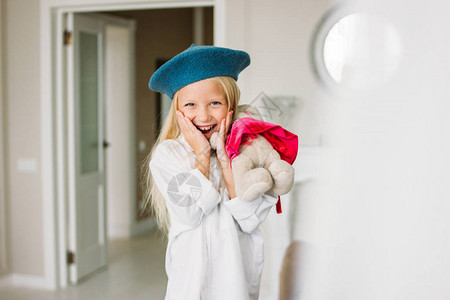 穿着白衬衫和蓝贝雷帽的漂亮时尚美发小姑娘手拿着玩具图片