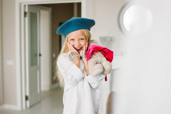 穿着白衬衫和蓝贝雷帽的漂亮时尚美发小姑娘手拿着玩具图片
