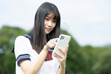 触摸智能手机屏幕的亚洲女中学生asia图片素材