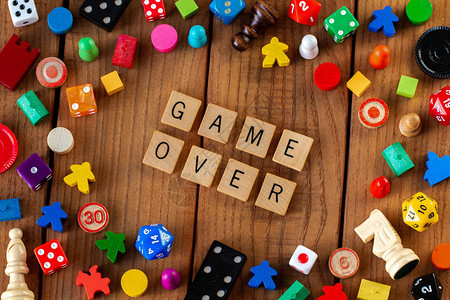 游戏结束用木制字母瓷砖拼出被骰子纸牌和其他木制背景上的图片