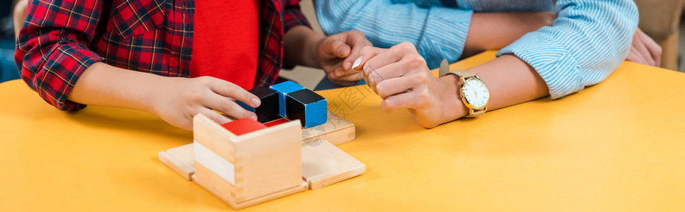 老师和小孩在蒙多索里班桌边打建筑砖的剪切视图片