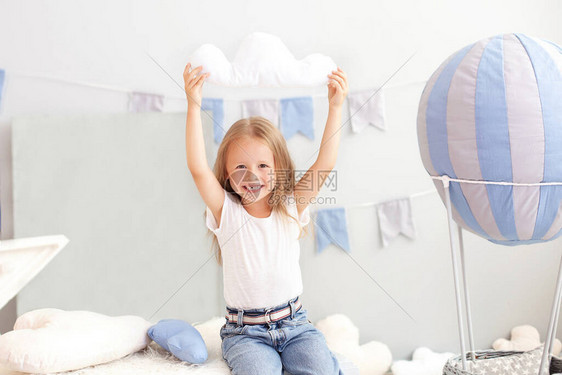 一个穿着休闲服的小女孩拿着一个云枕图片