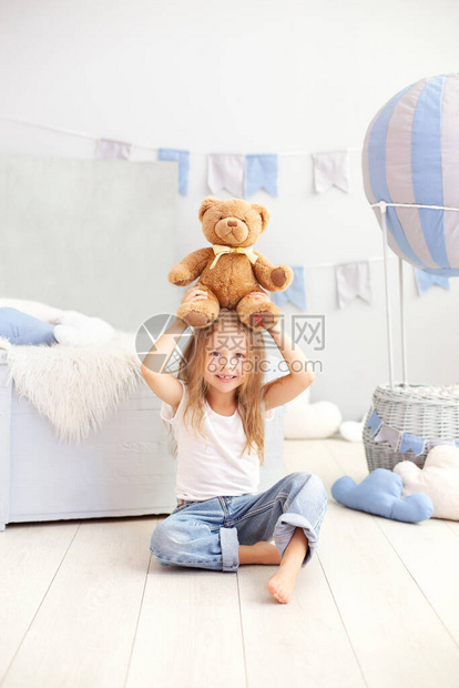 金发小女孩在装饰气球的背景上拿着一只泰迪熊孩子在儿童房里玩具童年图片