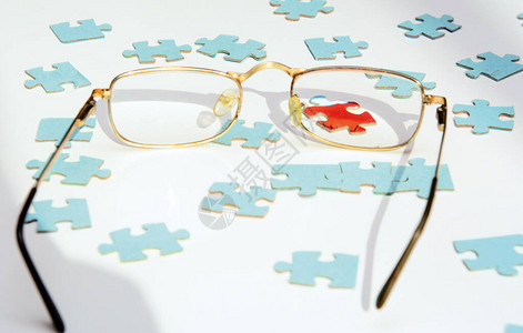 在白色背景蓝色拼图透过眼镜的片可以看到一个红色的拼图概念图片