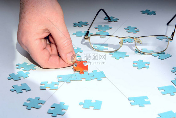 在白色背景上的谜题里面一个红色拼图由女手指握住眼镜概念图片