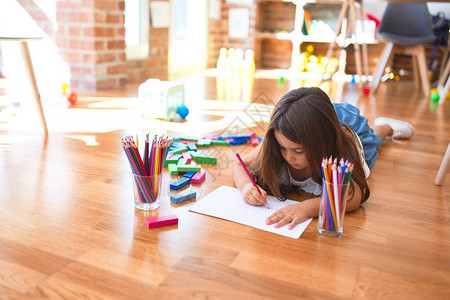 幼稚园用纸和铅笔躺在地板上绘画的可爱图片