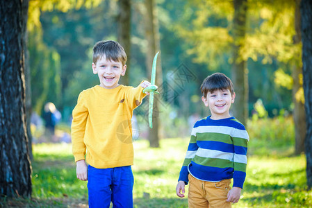 快乐的两个兄弟孩子在蓝色的夏日天空背景下玩具飞机男孩们在森林或公园里扔泡沫飞机最图片