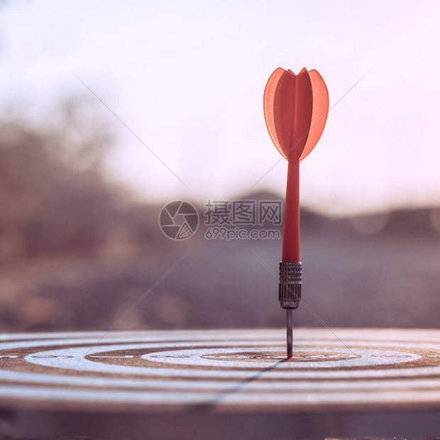 红色飞镖箭在日落的背景中击目标中心达板商业目标与焦点概图片