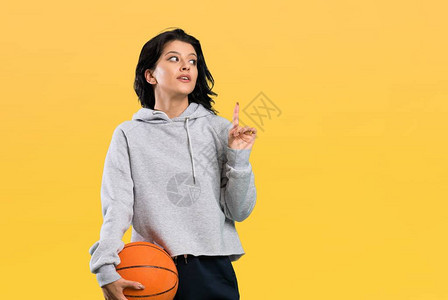 打篮球的年轻女子打算在孤立的背景上举起手指来图片