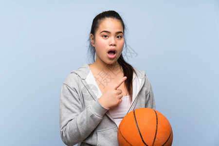 亚裔年轻女孩在孤立的背景中打篮球感到惊图片