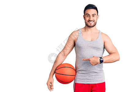 年轻英俊男子拿着篮球微笑着快乐地用图片