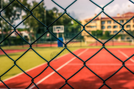 露天网球场和篮球场或金属栅栏后面的场地人造甲板禁止方法或无法进入的网球场角落拍摄图片