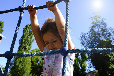 小女孩爬上游乐场的绳索童年概图片