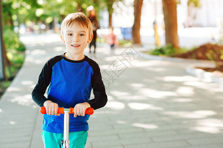 快乐的男孩骑在夏日公园的滑板车上健康的生活方式和运动休闲孩子在户外度过活跃的时间孩子们学习滑旱冰图片