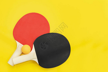 亮黄色背景上的两个乒乓球拍图片