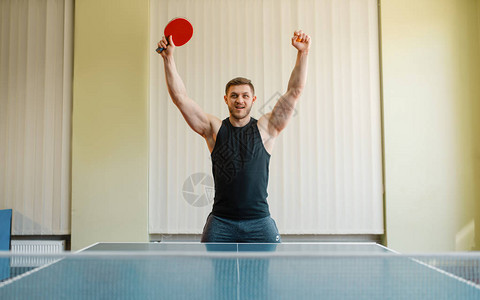 有乒乓球拍的快乐男人举起手图片