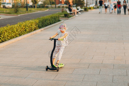 在城市街道上使用踏板车的小女孩图片