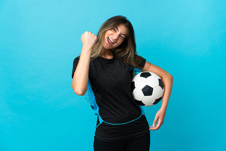 年轻女足球运动员在庆祝胜利的蓝背景下被孤立于孤单的青橄图片