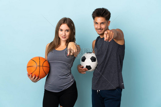 年轻一对打橄榄球和篮球的年轻夫妇在蓝背景点上被孤立图片