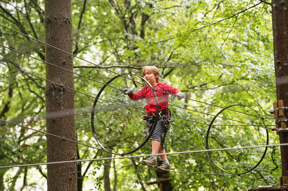 森林探险公园中小男孩高在绳上行走图片