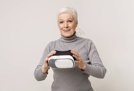 现代技术和老年老妇人在使用VR耳机后对体验虚拟现实感到惊讶图片
