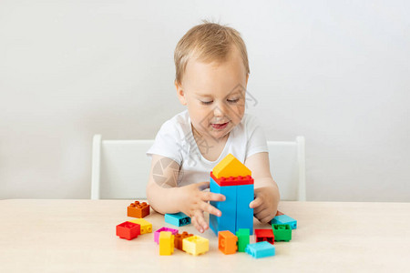 一个2岁的男孩坐在白色孤立背景的桌子旁图片