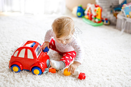 可爱漂亮的小女婴在家里或托儿所玩教育木制玩具健康快乐的蹒跚学步的孩子在室内有五颜六色的红色汽车孩子学图片