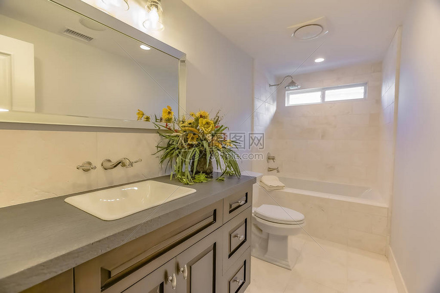 浴室内部可以看到内置浴缸马桶和梳妆台灰色的台面上放着一株开黄图片