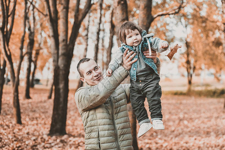 一位年轻父亲在秋天公园怀上一个孩子图片