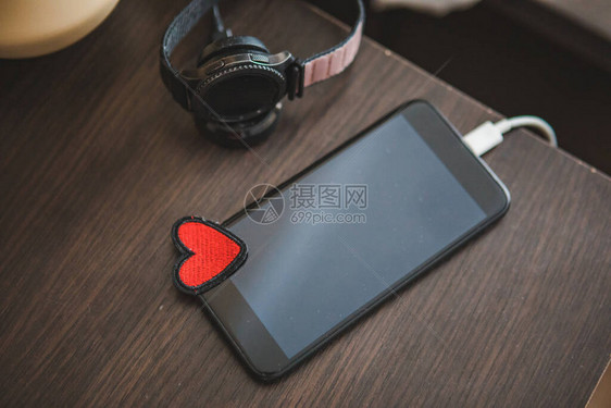用智能手表充电的智能手机红色爱心符号在线约图片