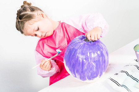 小女孩用紫色丙烯颜料画小工艺南瓜图片