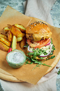 芝士汉堡用薯条生菜西红柿和蛋黄酱在黑桌图片
