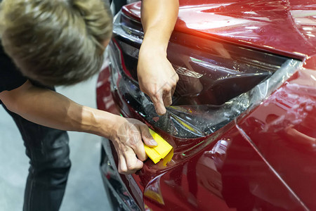 工人用抹刀安装汽车漆面保护膜背景图片