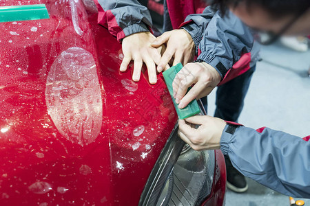 工人用抹刀安装汽车漆面保护膜图片