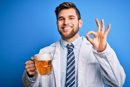 金发大胡子和蓝眼睛的金黄色年轻医生男子穿着大衣喝着啤酒图片