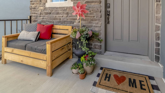 用木椅盆栽植物花环和门垫装饰的家全景门廊这所房子有一个灰色的玻璃前图片