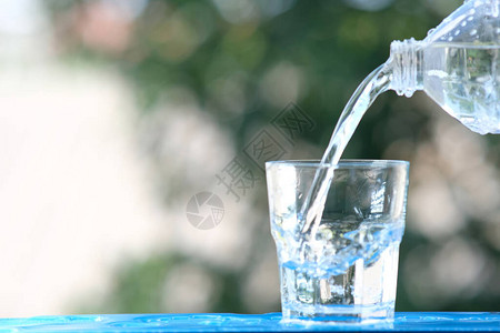 木桌背景上的一杯水和倒饮用水背景图片