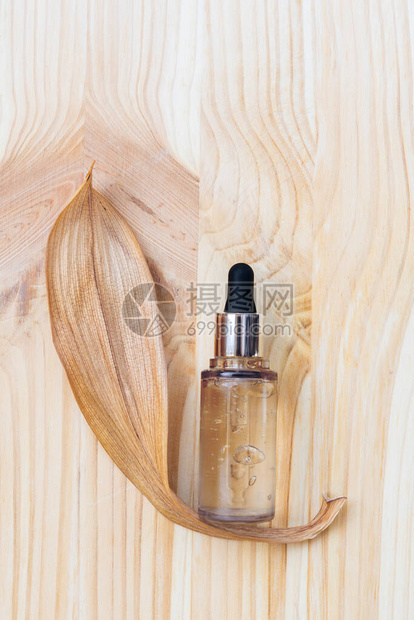 含白叶木棕色背景和干叶的有皮肤护理血清的水管玻璃瓶图片