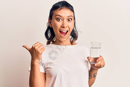 年轻女子喝杯水用指头向侧面微图片
