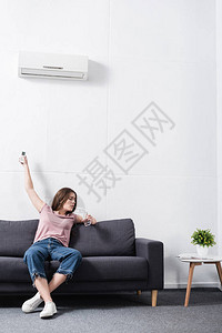 心烦意乱的年轻女子在受热和试图开空调时图片