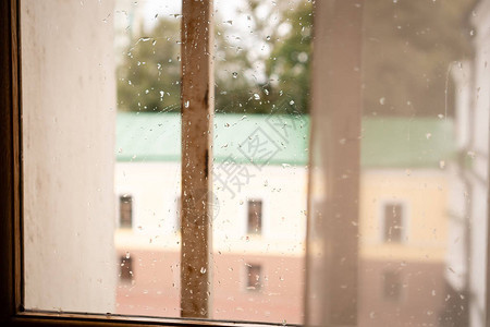 有雨滴的窗口窗外是一栋绿色屋顶窗户和黄褐图片