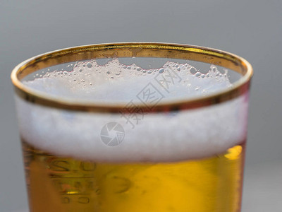在新倒的金边啤酒杯中近距离观察泡沫图片