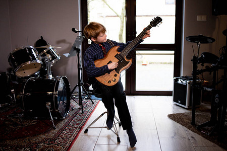 小男孩在家弹吉他待在家里背景图片